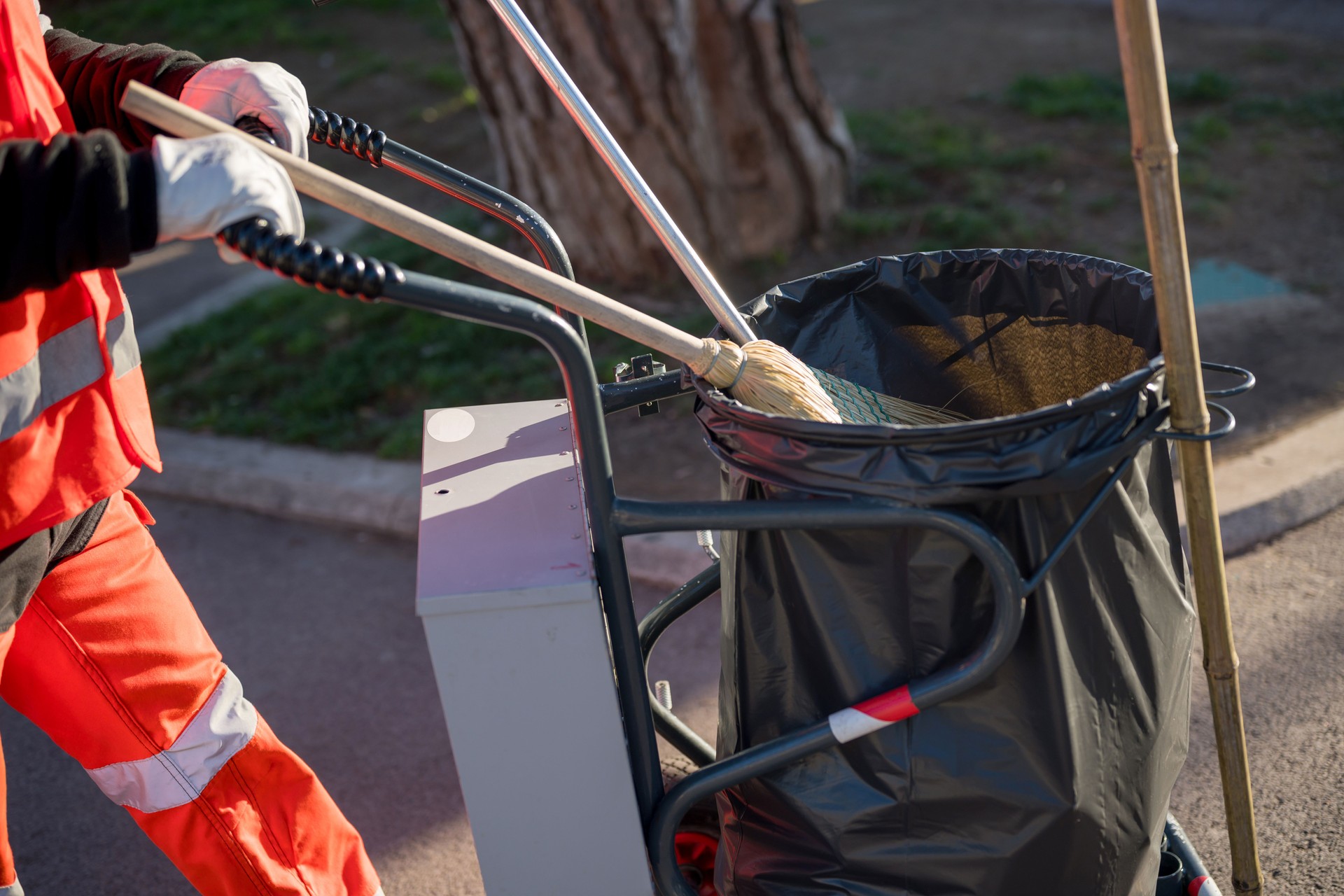 Sanitation worker pushing garbage bin